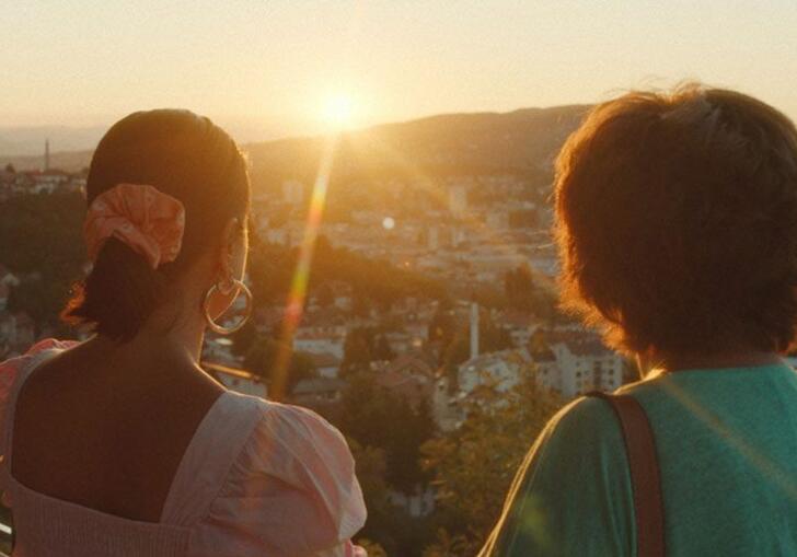 Two women facing a sunlit valley