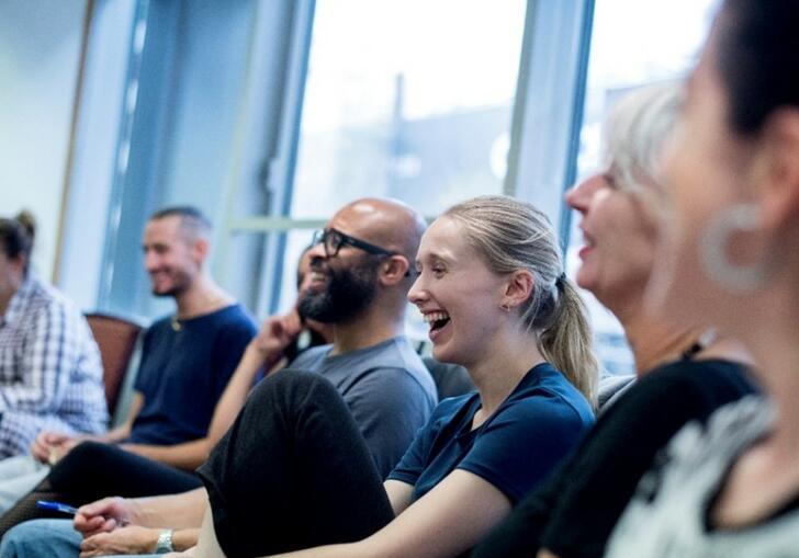 A group of teachers sit in a room laughing. 
