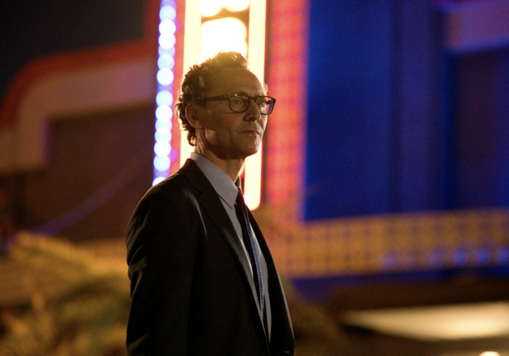 Tom Hiddleston stands in front of a vintage cinema