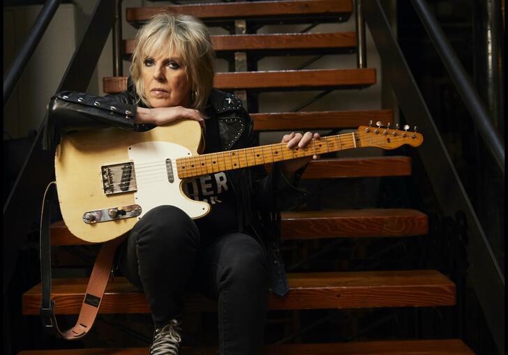 Photo on Lucinda Williams sitting on the steps with guitar