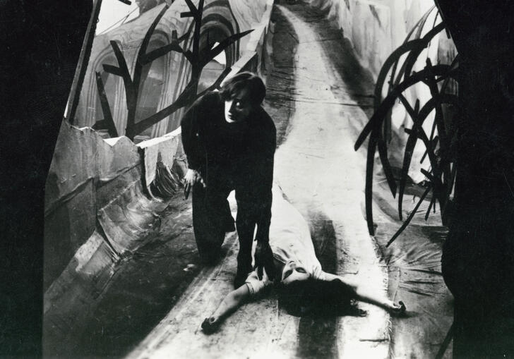 A man in a distorted walkway with a woman lying on the floor.