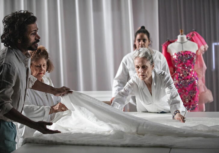 Four people gather around a large piece of white fabric.