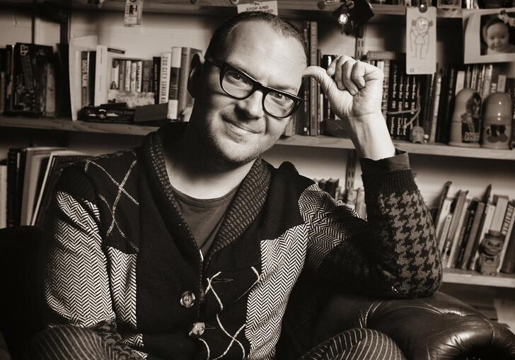 Black and white portrait of Cory Doctorow sitting in an armchair