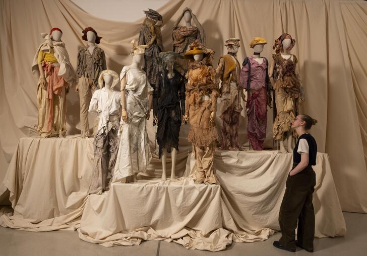 A woman looks at a collection of earth-toned outfits by designer Paolo Carzana.