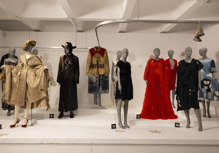 A woman looks at a collection of outfits by a range of designers.