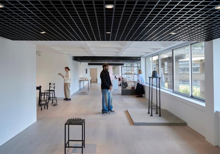 A photo looking down the gallery, with people looking at artworks in the exhibition.
