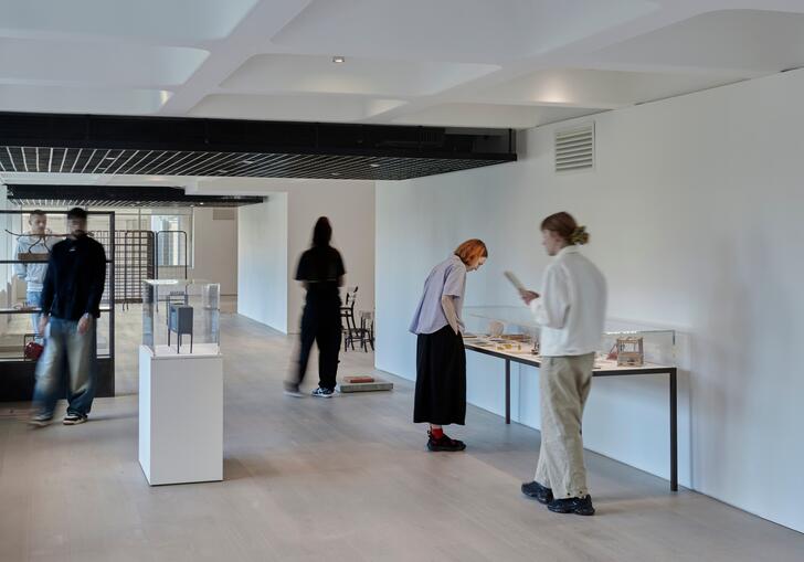 A photo looking down the gallery, with people looking at artworks in the exhibition.