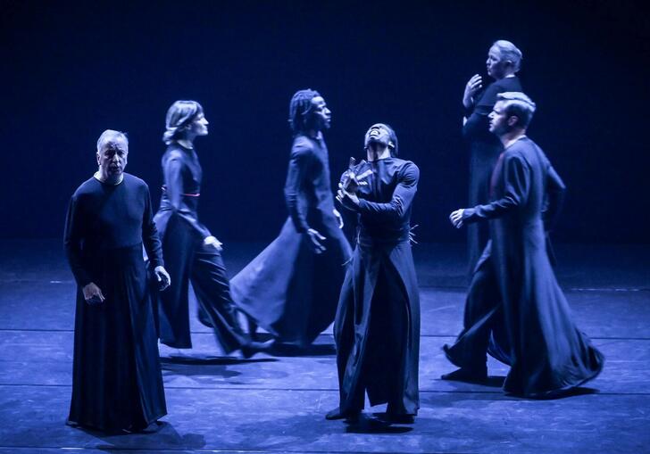 Performers dressed in black gowns on stage. 