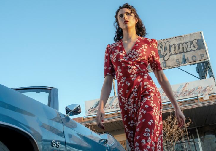 Margaret Qualley strides determinedly in a red floral dress