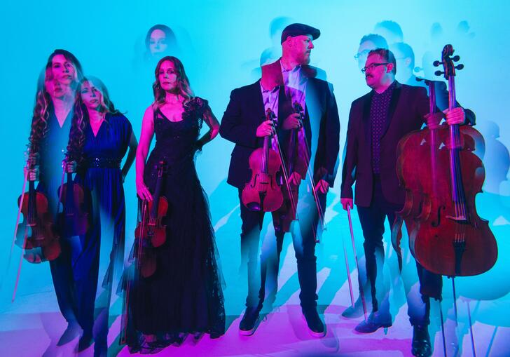 Vitamin String Quartet in front of a blue background 