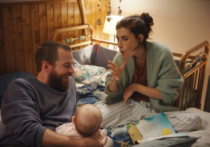 A family sit in bed with their baby