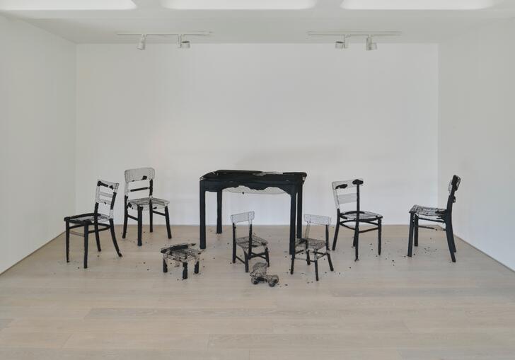 A set of tables and chairs, all burnt out and their charred remains revealing their chicken wire frames.