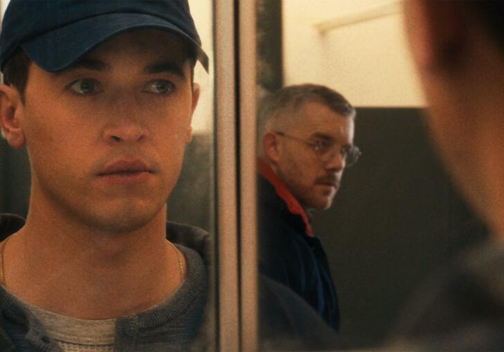 Two man looking at each other through a mirror