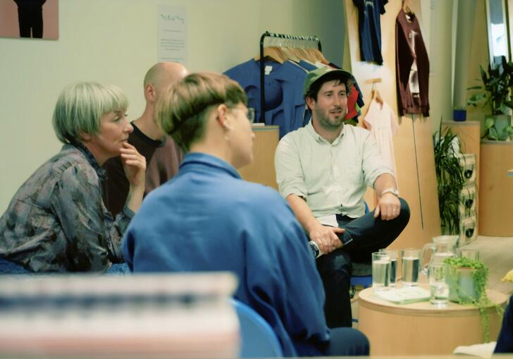 A group of people sit in a room and talk.