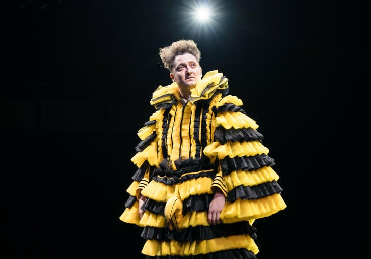 A person stood on stage wearing yellow and black 