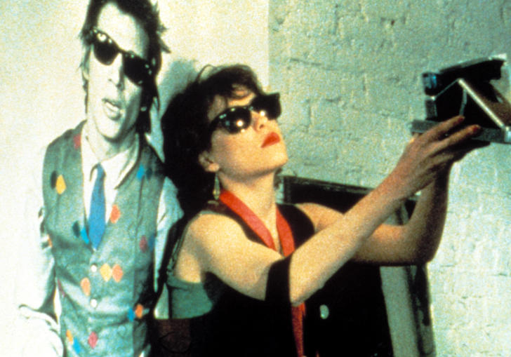 Photo still from Smithereens film of woman in sunglasses taking a Polaroid photo