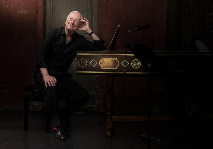 Image of conductor William Christie by a harpsichord