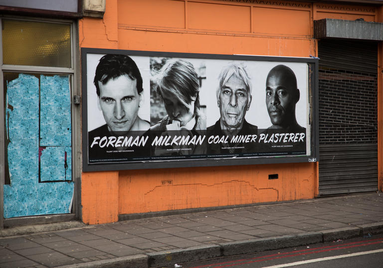 Four posters pasted to an orange wall