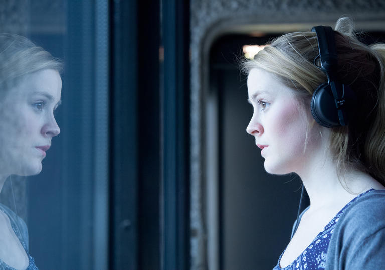 Photo of woman wearing headphones looking out of a window