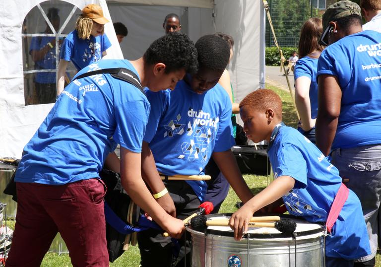 three people playing a metal drum