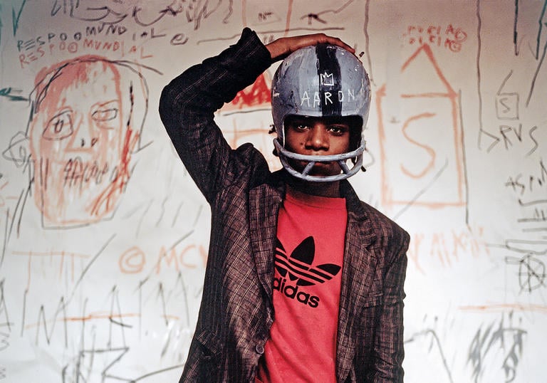 Photo of Basquiat wearing an Adidas tshirt, suit and football helmet