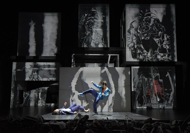 two dancers on stage against a backdrop of black and white paintings