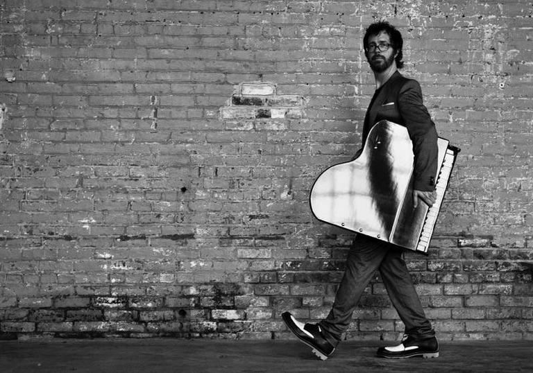 A giant Ben Folds holds a grand piano under his arm or a normal sized Ben Folds holds a miniature piano under his arm - who knows? Either way it's a lot of fun !