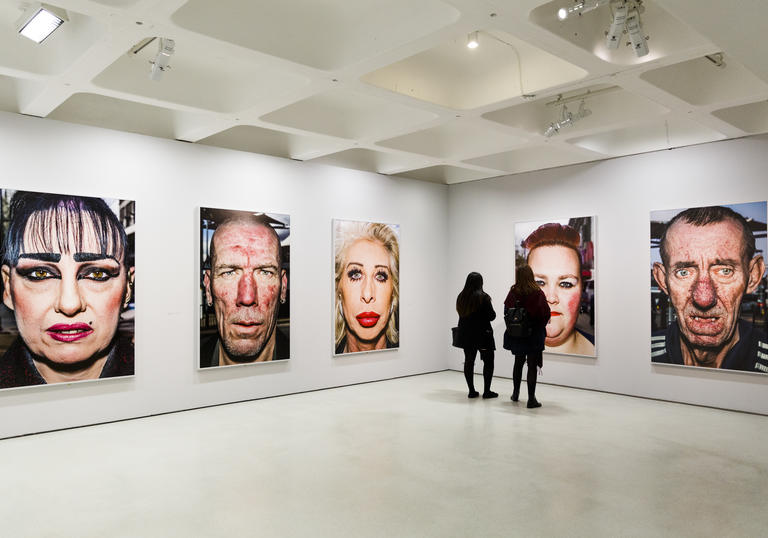 Two people looking at large colour photographs of faces