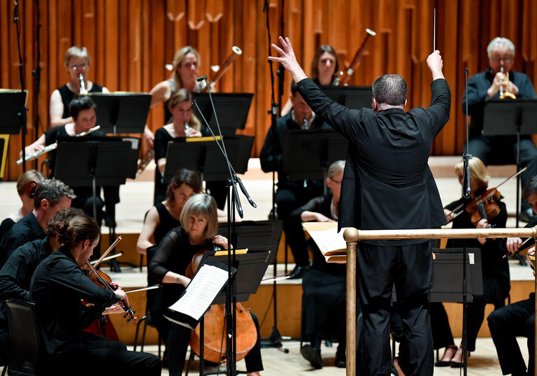 photo of britten sinfonia and man conducting an orchestra