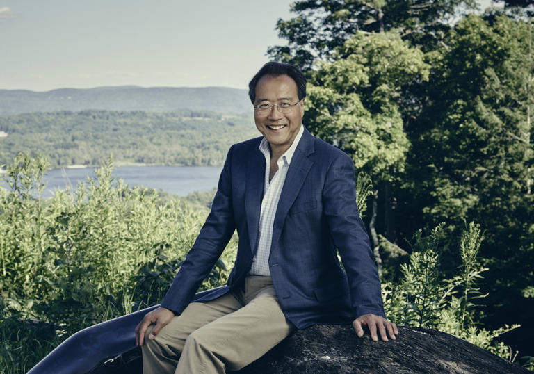 Yo Yo Ma sitting on a rock