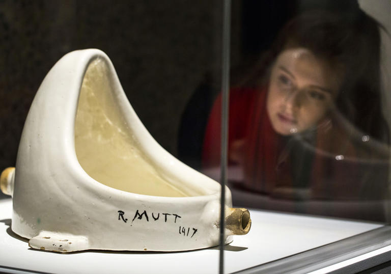 A woman looks at Duchamp's urinal sculpture, Fountain