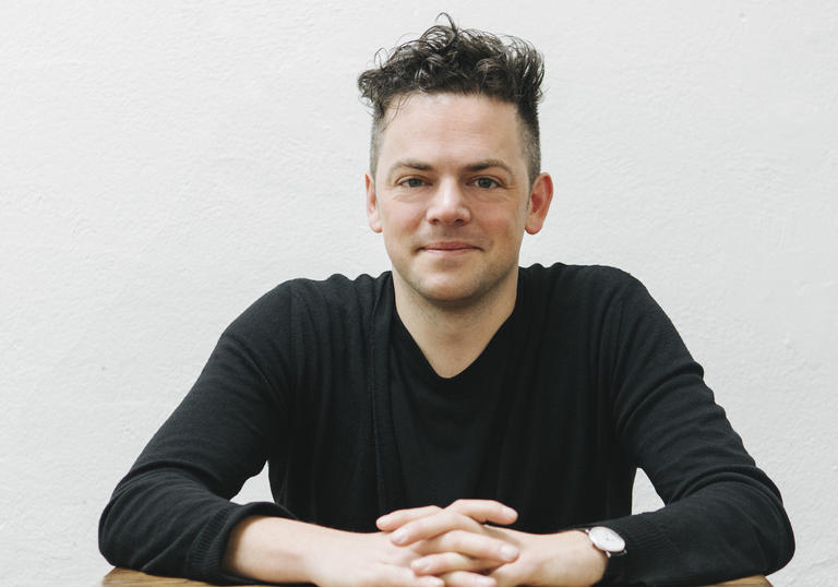 Nico Muhly sitting at desk 2017