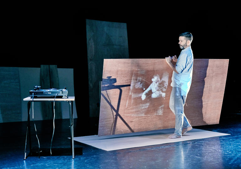 Man carries large piece of wood with projection on it.