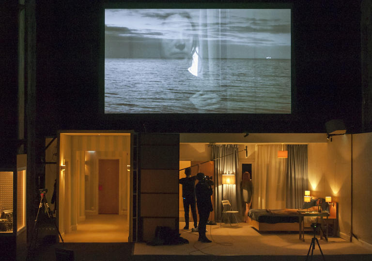 Video of woman with sea in the background. A film set below in a woman's bedroom. A woman in a recording box.