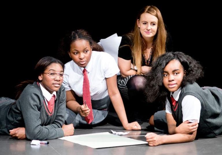 four students crouched on the floor