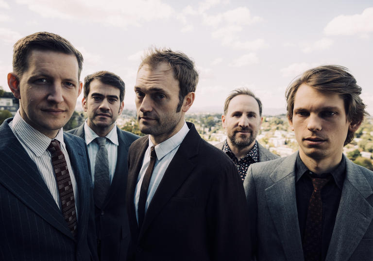 Punch Brothers in suits standing in a field