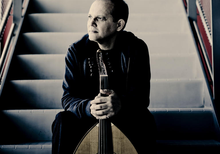 Anouar Brahem sitting on a staircase holding his oud