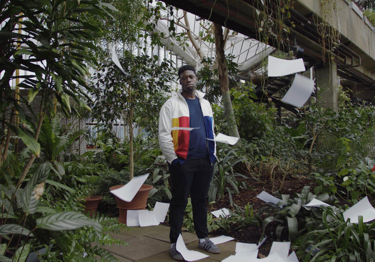 Man standing in conservatory surrounded by paper