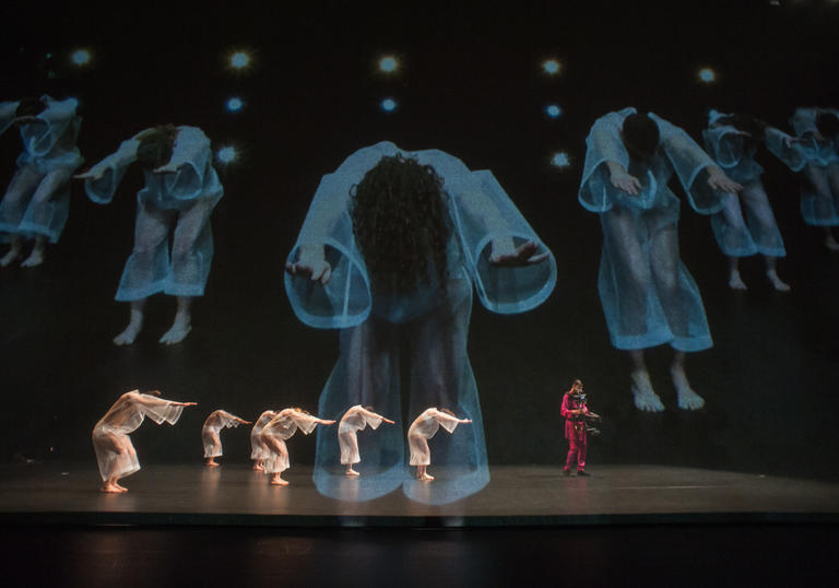 A group of dancers with video in the background