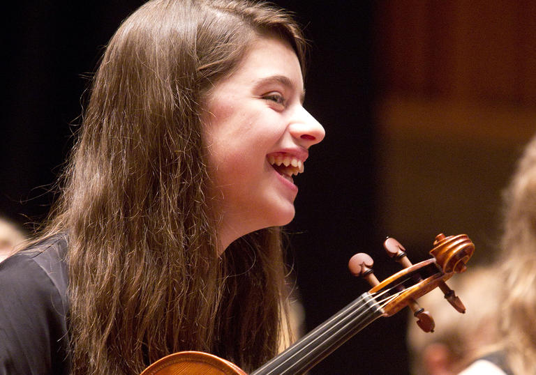 photo of woman smiling and holding a violin