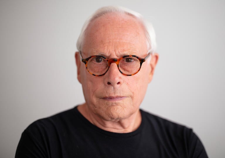 Dieter Rams is wearing a pair of tortoise shell spectacles and a black t-shirt 
