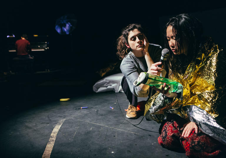 Girl looking at water bottle and talking into microphone