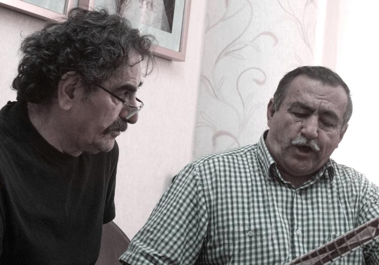 Shahram Nazeri and Davlatmand Kholov sitting together with their instruments