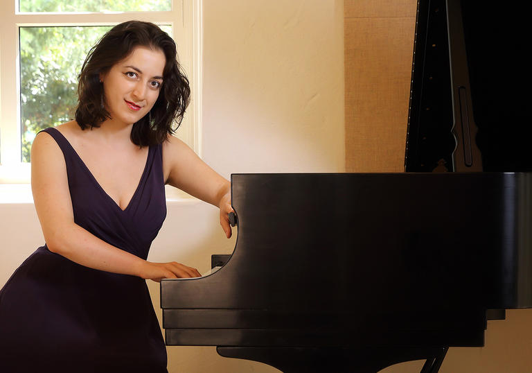 Pianist Sophiko Simsive sits by a piano