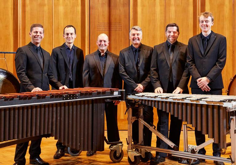 The LSO Percussion Ensemble stands behind orchestral percussion instruments