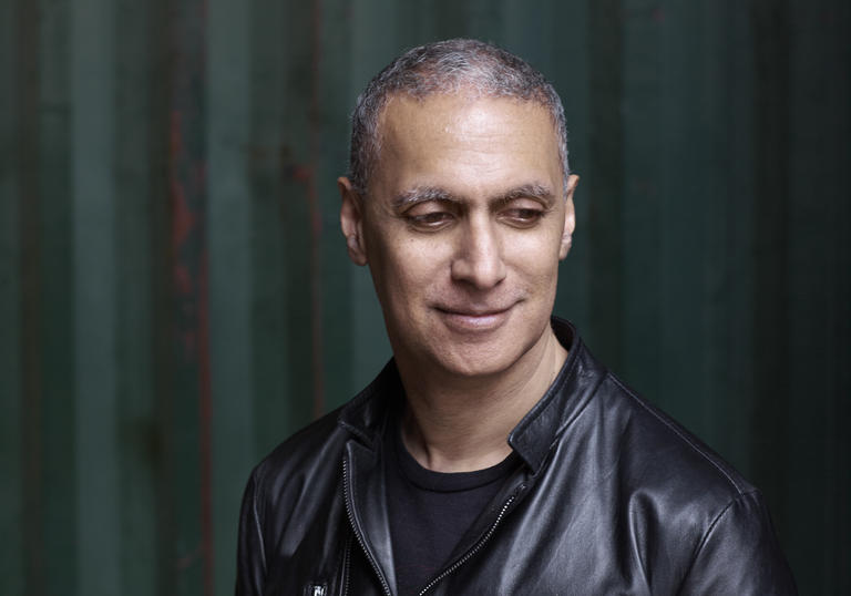 Picture of Nitin Sawhney looking down in a black leather jacket
