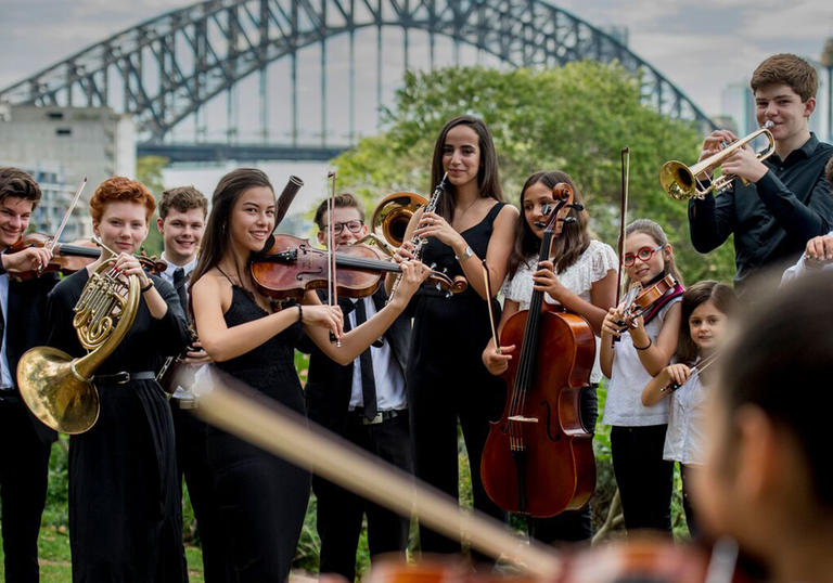 Players in the Sydney Youth Orchestra perform in front of Sydney Harbour Bridge