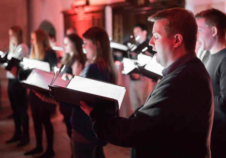 The Ora Singers performing in red lighting