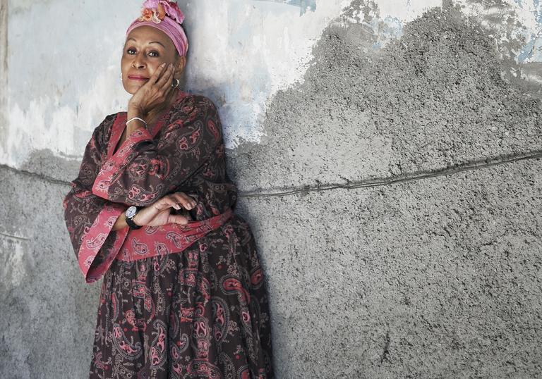 Omara Portuondo in front of a painting of the Cuban flag