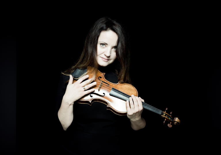 Baiba Skride with violin dark background